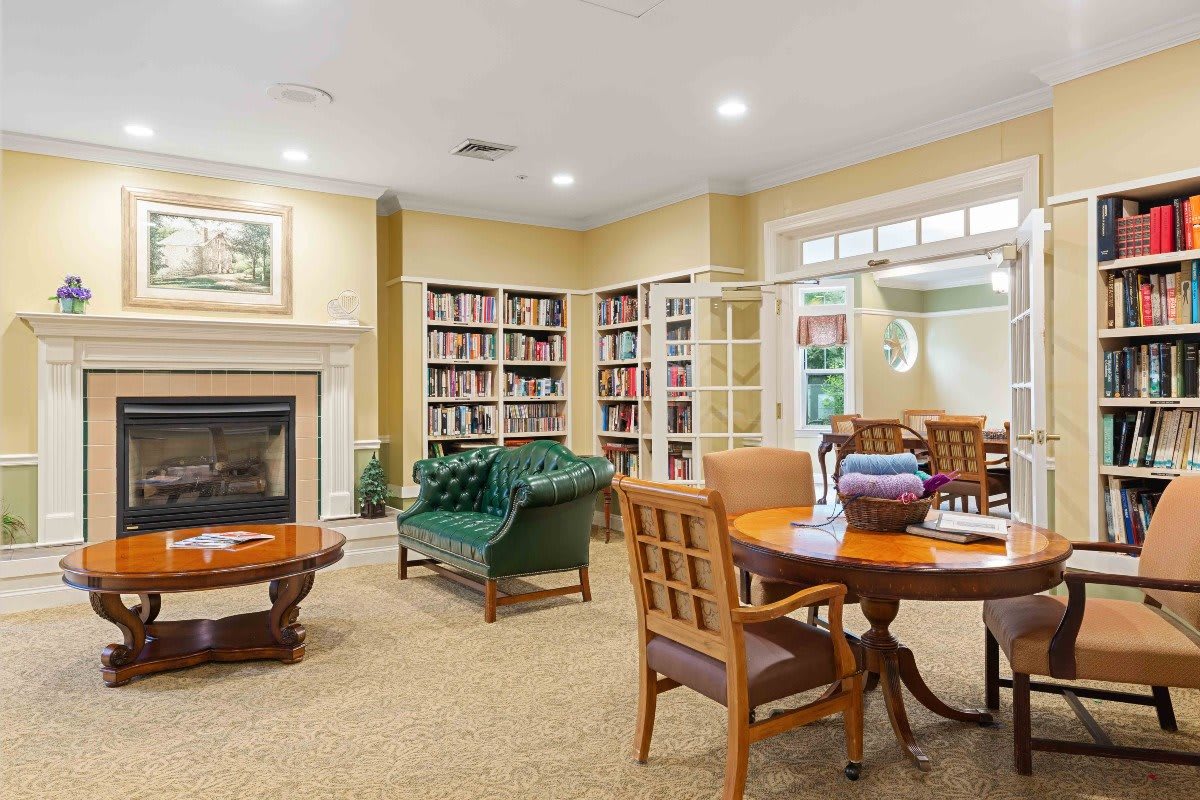 A cozy library with bookshelves, a fireplace, and comfortable seating.