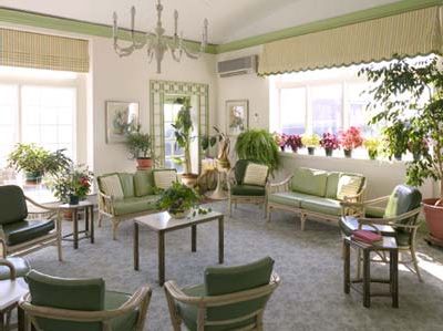 A bright living room with green furniture and an abundance of plants.
