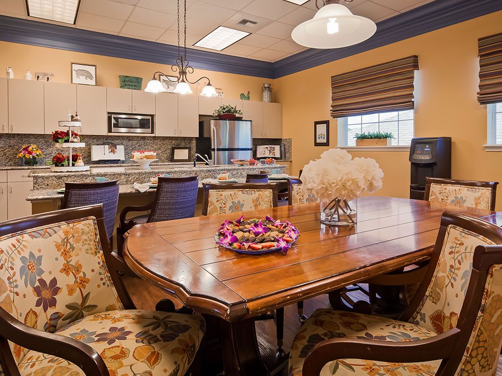 A cozy kitchen and dining area with a wooden table, floral chairs, and modern appliances.