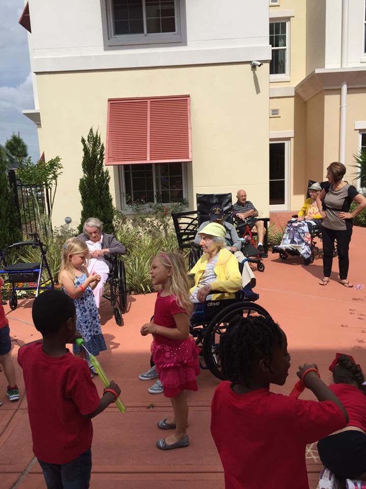 Children and elderly people enjoying a sunny day outdoors together.