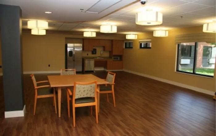 An empty dining area with a kitchen in the background.