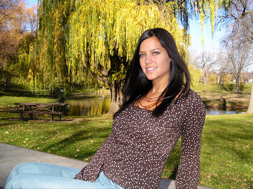 A woman enjoying a sunny day outdoors in a park surrounded by vibrant greenery.
