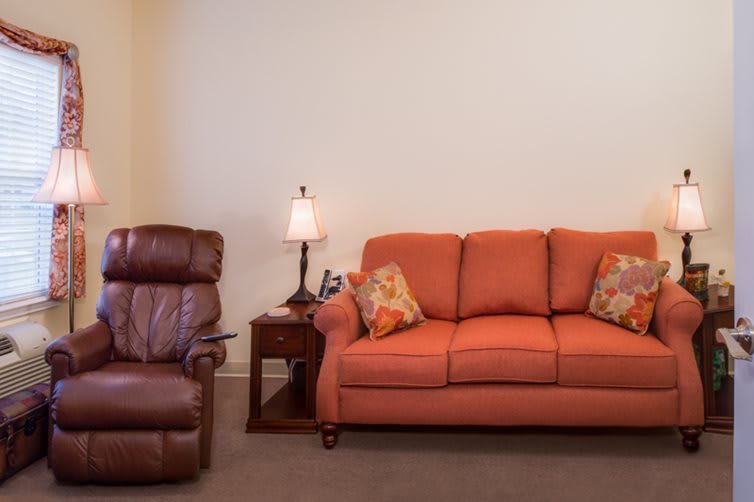 A cozy living room setup with a recliner and an orange sofa adorned with decorative cushions.