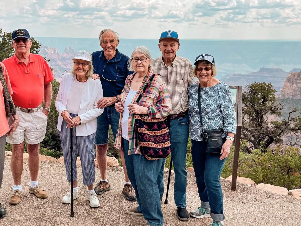 A group of seniors enjoying a day out in nature, posing together with a scenic background.