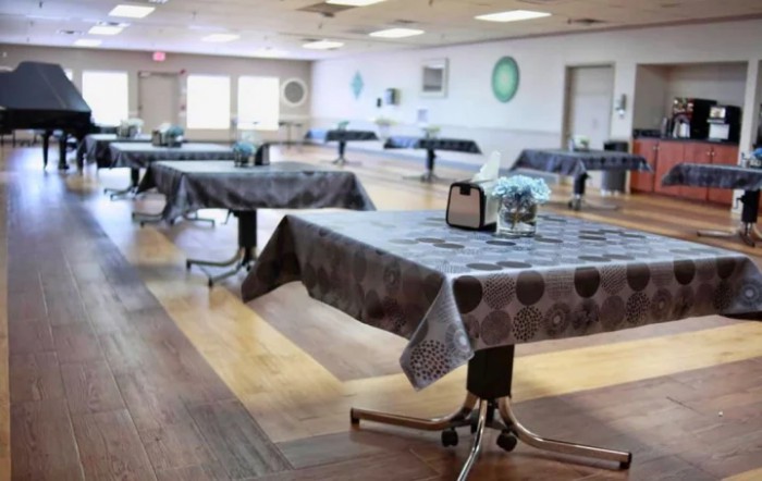 An empty dining hall with tables covered in patterned tablecloths.