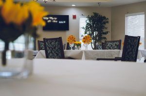 A cozy dining room with tables set and floral decorations.