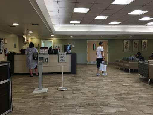 A spacious waiting area in a healthcare facility with reception desks and seating.