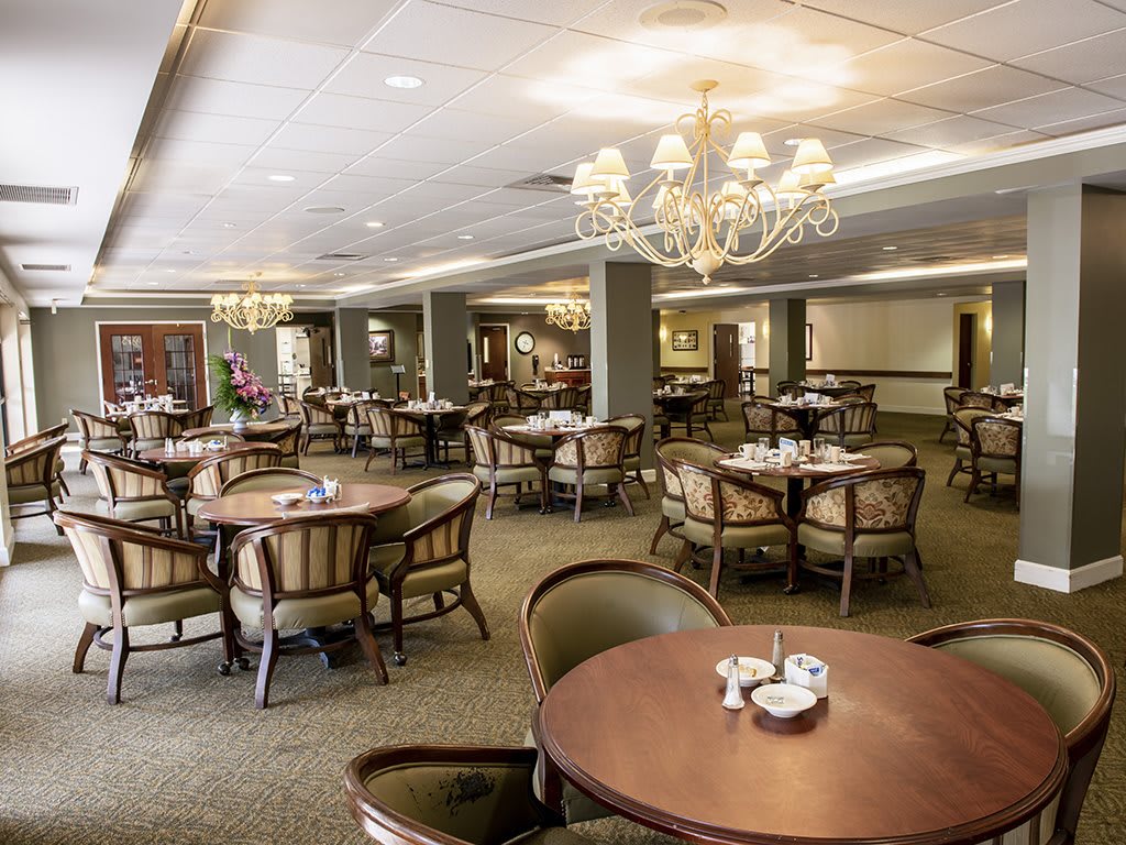 An elegant dining area with tables, chairs, and chandeliers creating a refined atmosphere.