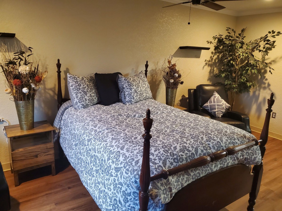 A cozy bedroom with a patterned bedspread and decorative pillows, complemented by indoor plants.