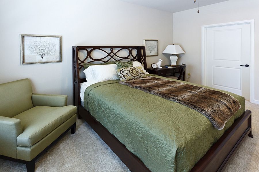 A cozy bedroom with a stylish bed featuring green bedding, complemented by decorative elements and furniture.