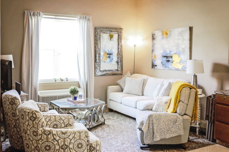 A cozy and bright living room with modern decor, featuring a comfortable sofa, stylish armchairs, and abstract artwork.
