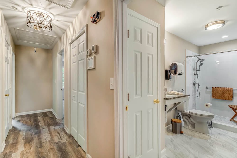 A well-lit hallway with multiple doors leading to a bathroom and laundry area.