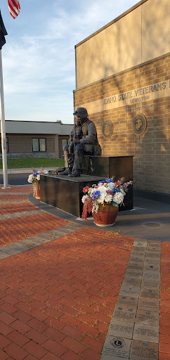 A solemn military statue adorned with flowers at a memorial site.