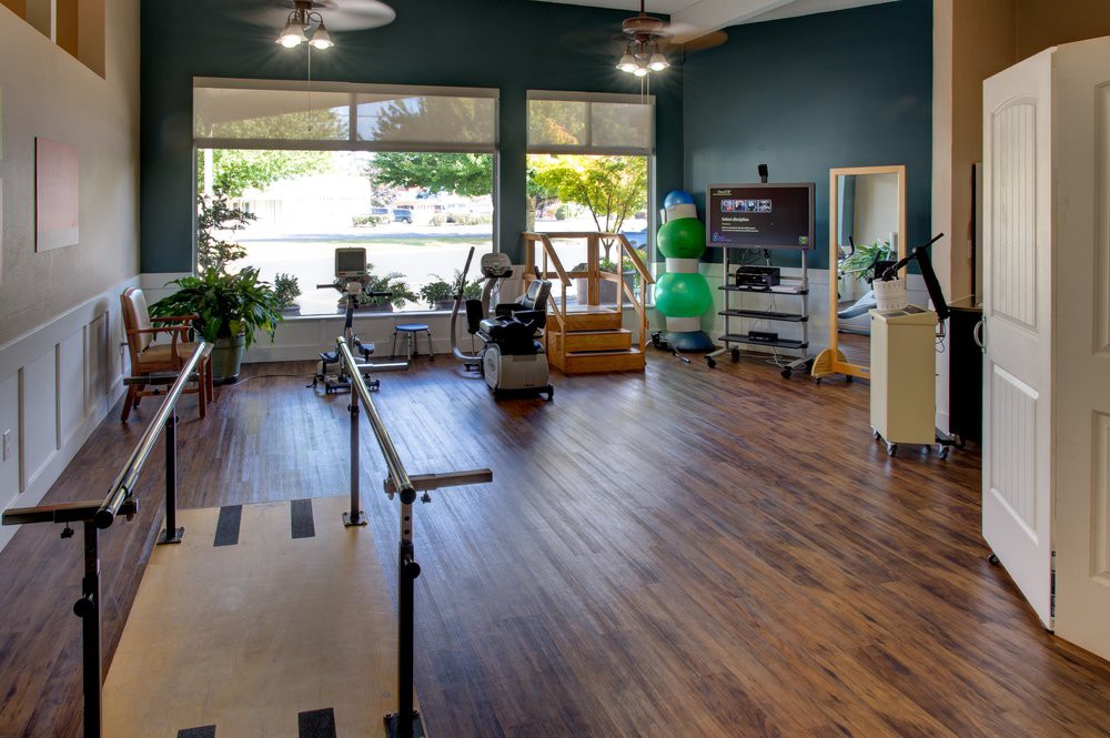 A well-lit physical therapy center equipped with exercise and rehabilitation equipment.