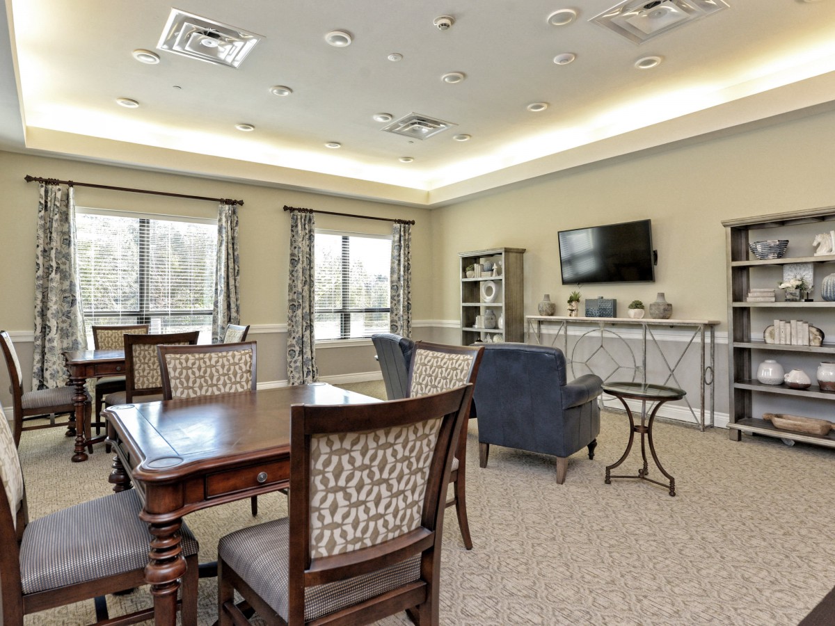 A well-furnished living room with a dining table, chairs, and a television.