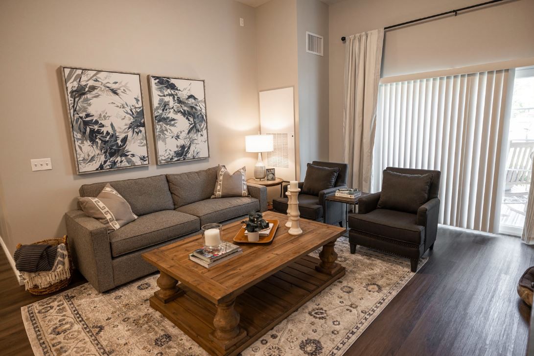 A modern living room featuring a gray sofa, two armchairs, wooden coffee table, and abstract artwork on the walls.