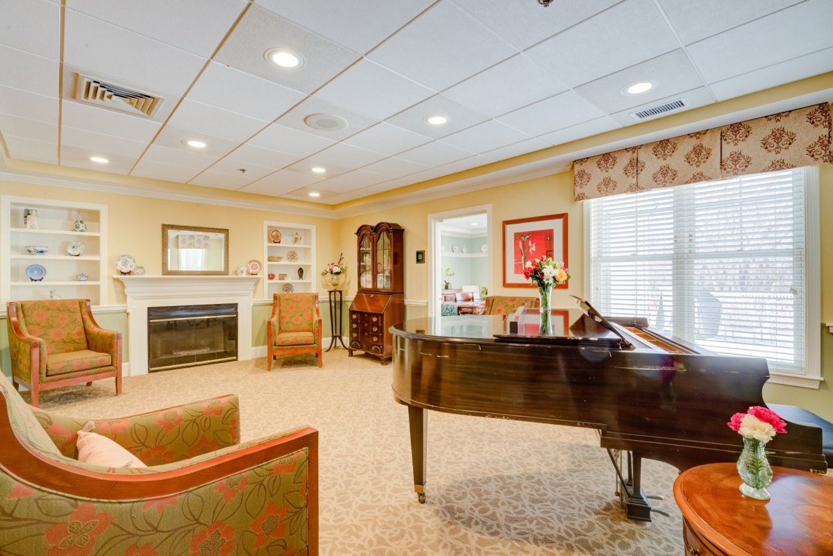 A cozy living room with a grand piano, fireplace, and comfortable seating.