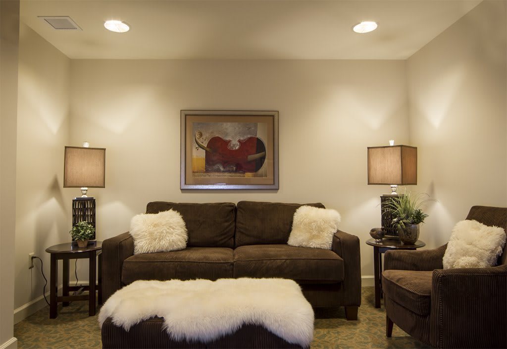 A cozy living room featuring a brown sofa and matching ottoman, complemented by soft lighting and tasteful artwork.
