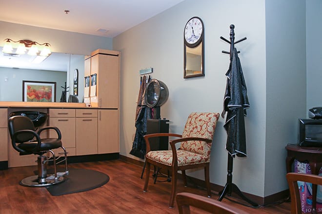 A cozy salon interior with a vintage-style chair, coat rack, and wall clock.