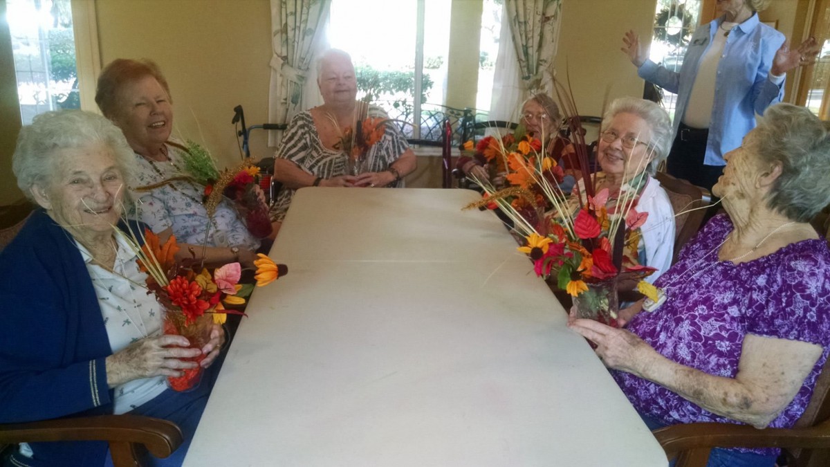 A group of elderly people sitting around a table decorated with flowers.