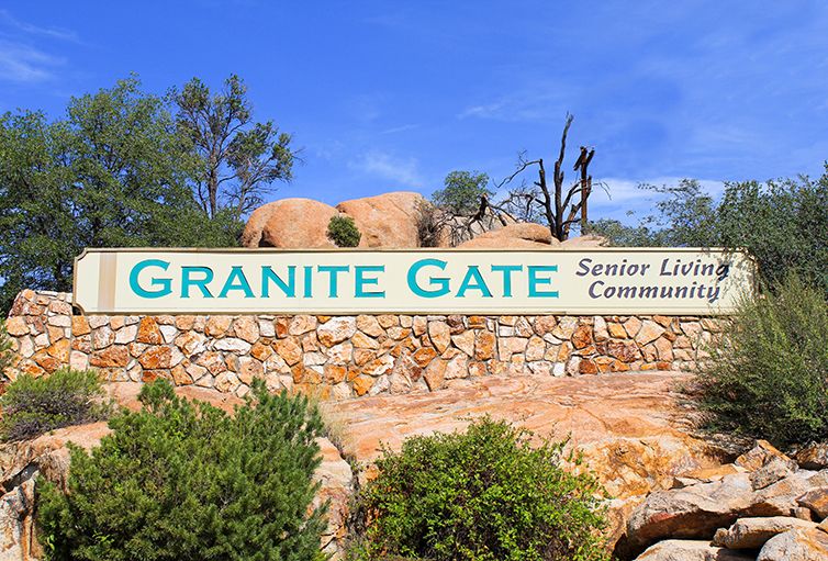 Entrance sign for Granite Gate Senior Living Community surrounded by natural stone and greenery.