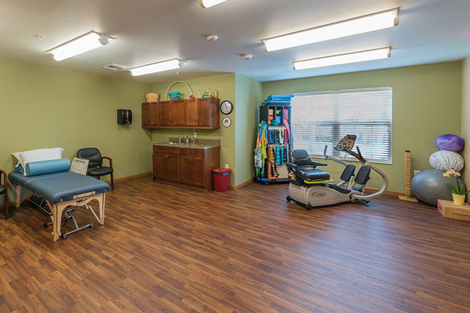 A well-equipped physical therapy room with exercise equipment and treatment tables.