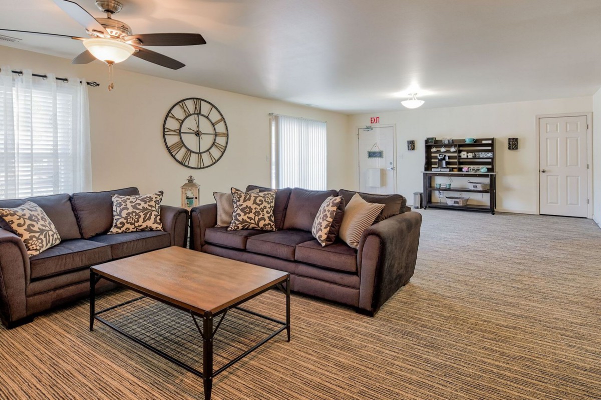 A cozy living room with a large wall clock and comfortable seating area.