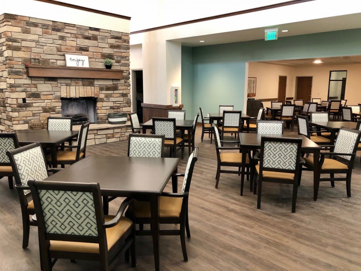 A modern dining area with neatly arranged tables and chairs, featuring a fireplace.
