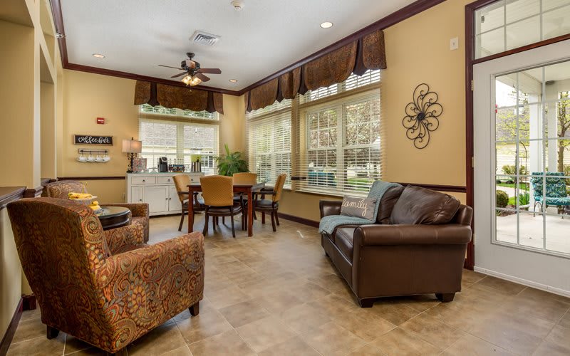 A cozy living room with large windows, a dining table, and comfortable seating.