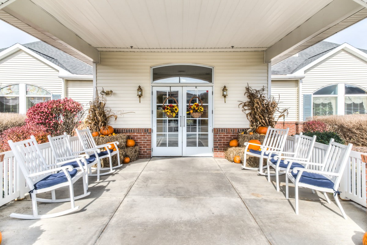 A welcoming porch decorated with pumpkins and chairs, showcasing autumn decor.