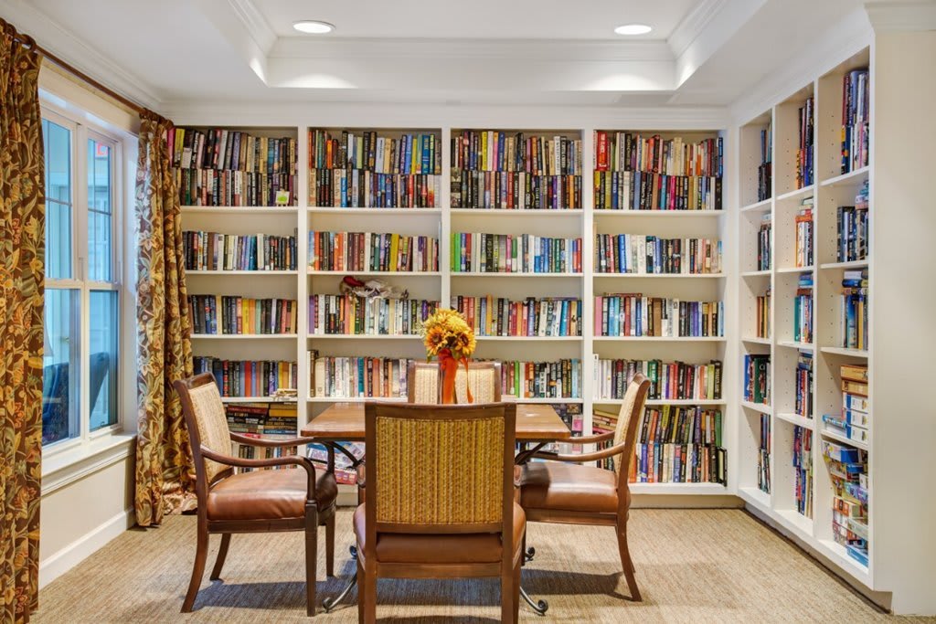 Cozy library with a table and chairs surrounded by bookshelves filled with books.