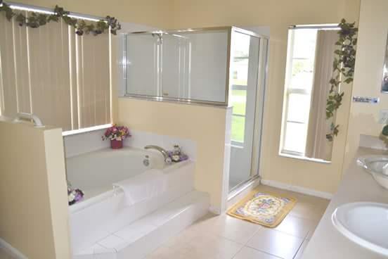 A bright and clean bathroom featuring a bathtub, shower, and large windows.