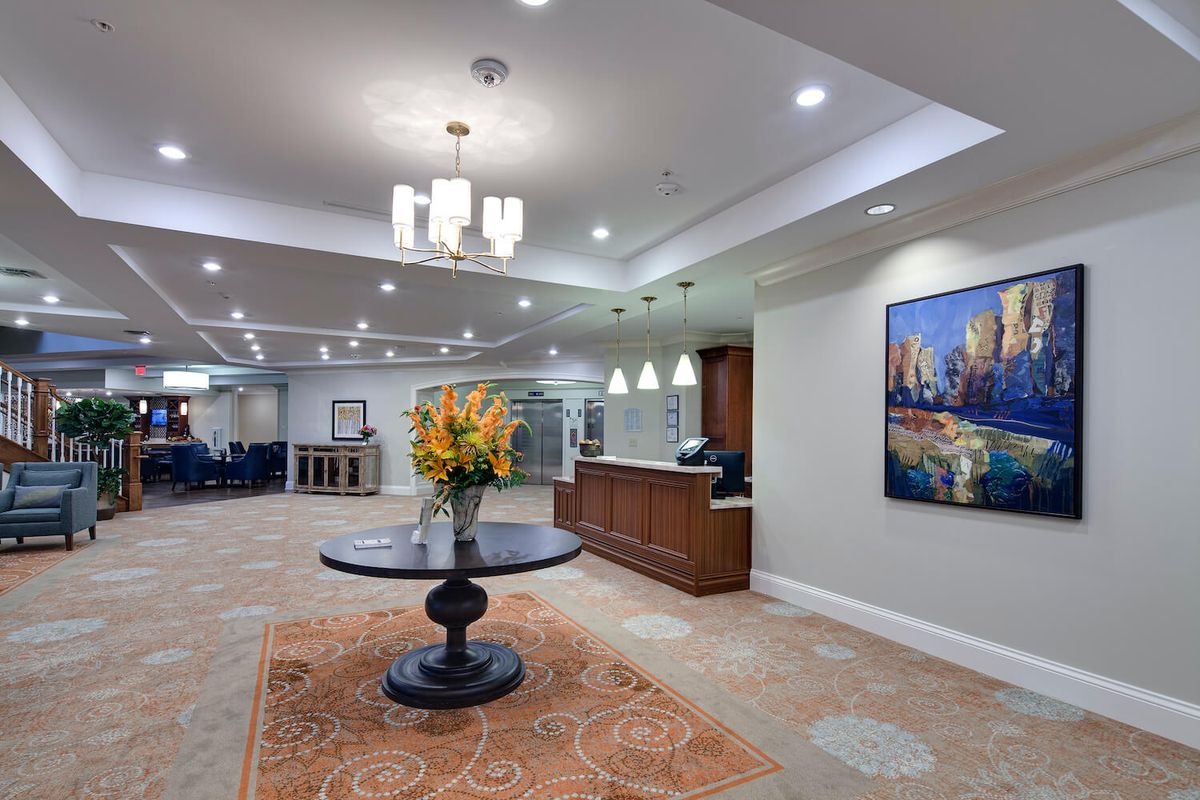 A spacious and elegantly designed lobby featuring a central table with flowers, a reception desk, and modern lighting fixtures.