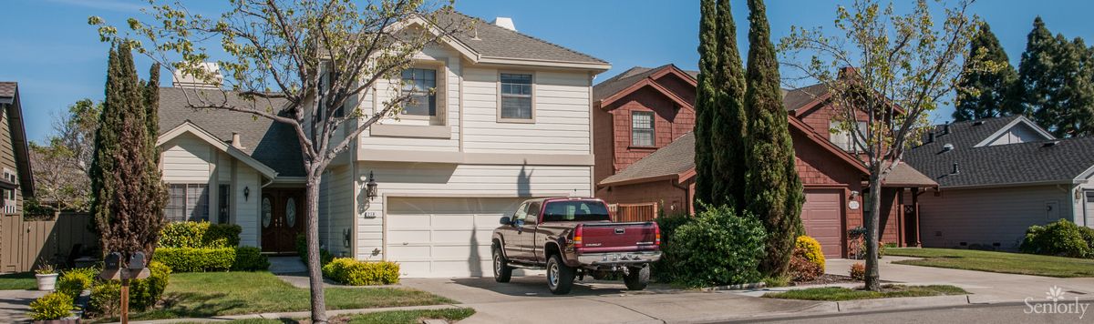 A suburban house with a truck parked in the driveway on a sunny day.