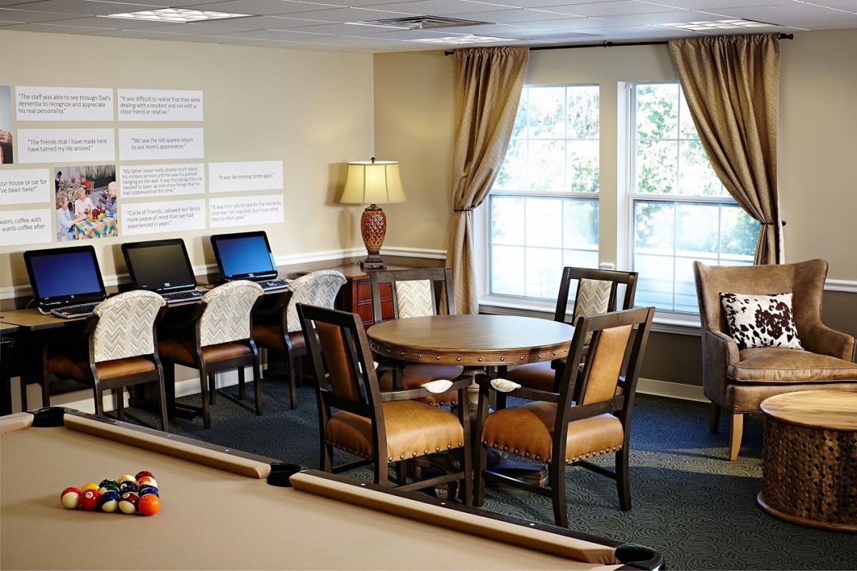 An office space with computers, tables, and chairs next to large windows.