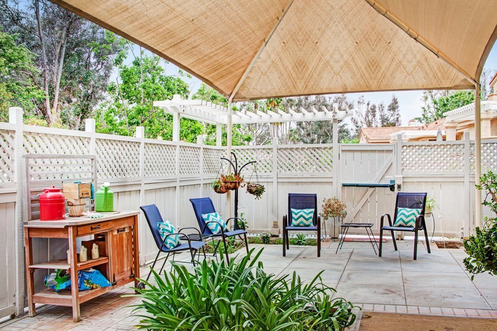 A cozy patio area with chairs under a canopy, surrounded by plants and decorative elements.