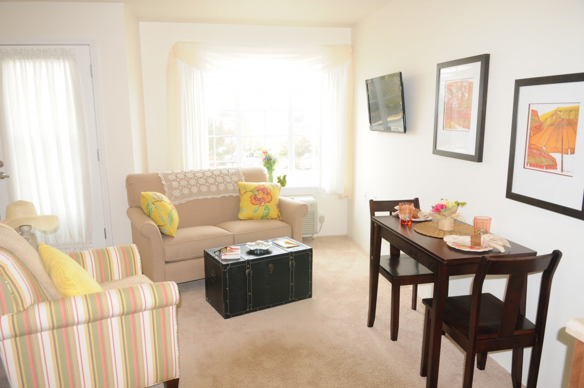 A cozy living and dining area with a sofa, table, and wall-mounted television.
