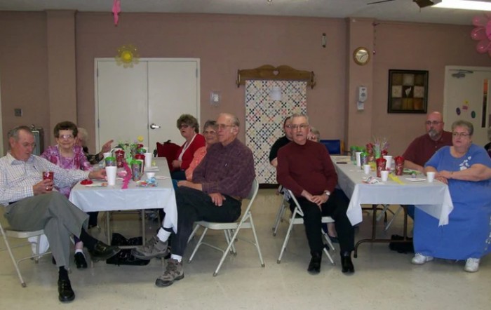 A group of people sitting at tables during an indoor social gathering.