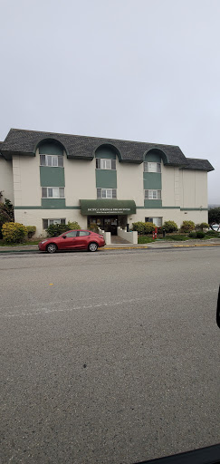 A hotel with a distinct architectural style, featuring a red car parked in front.