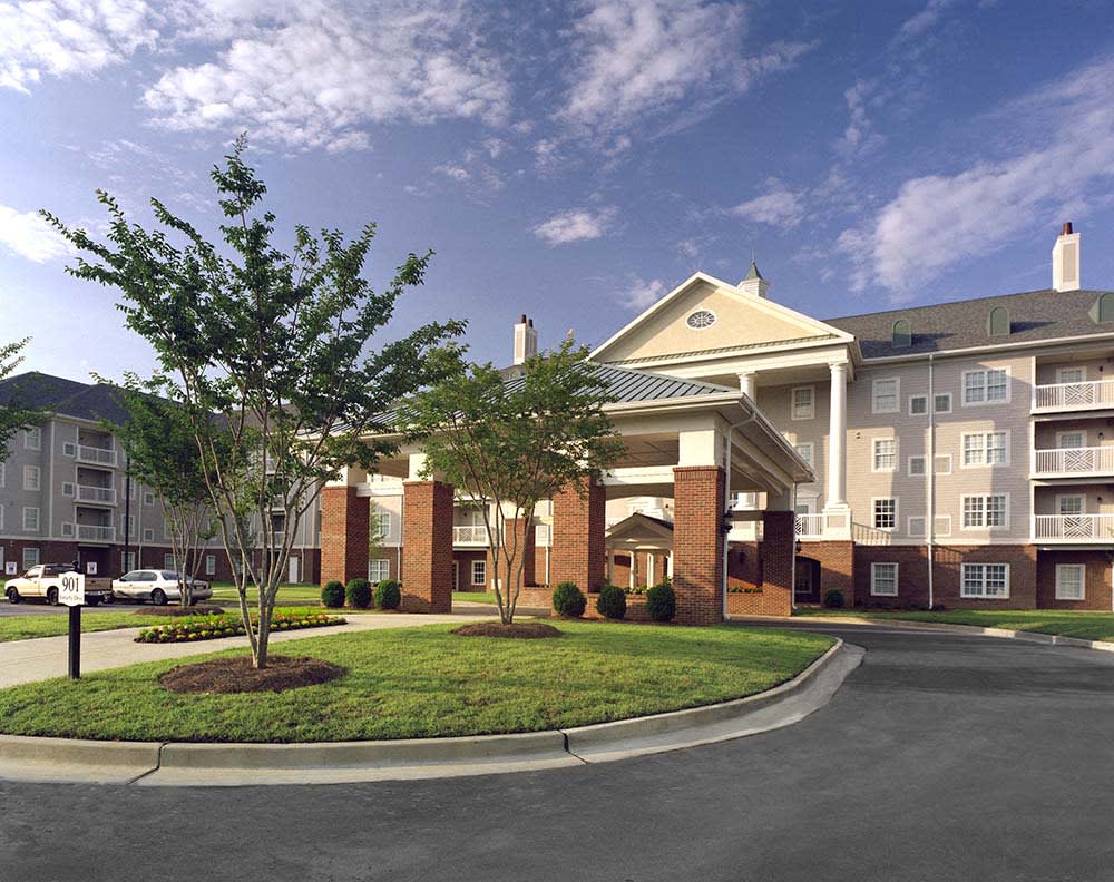 An exterior view of a hotel with well-maintained landscaping and clear skies.