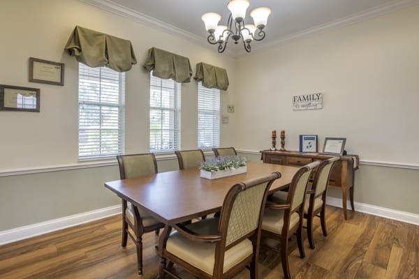 A cozy dining room with a wooden table, upholstered chairs, and a chandelier overhead.