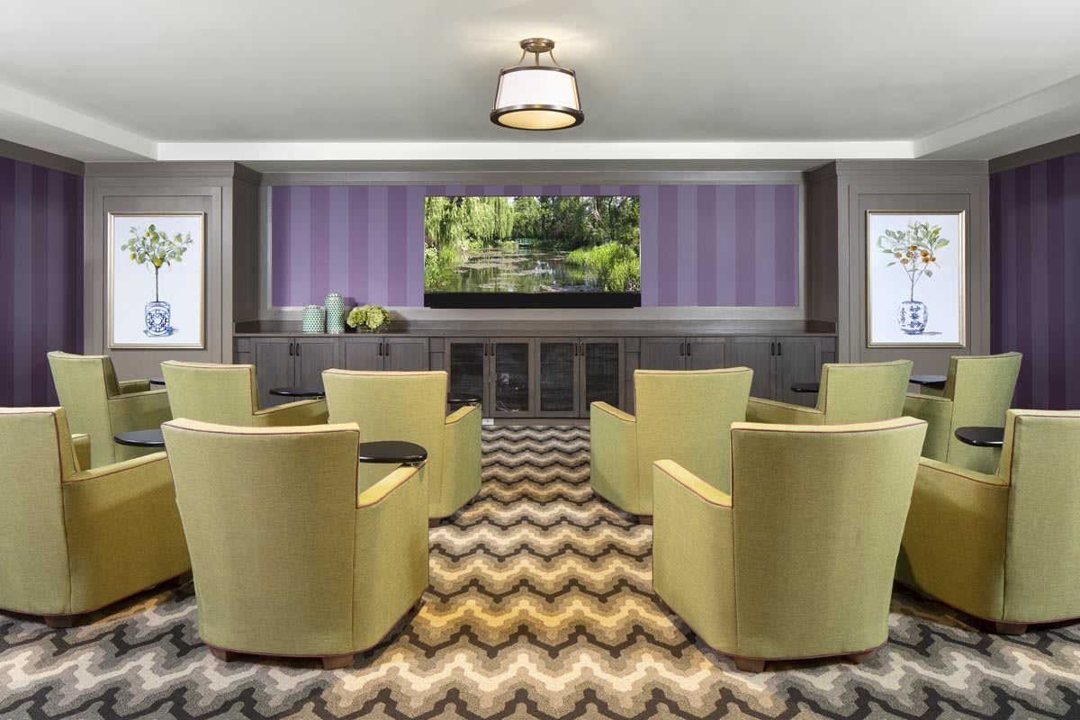 A modern conference room with green chairs and a large television.