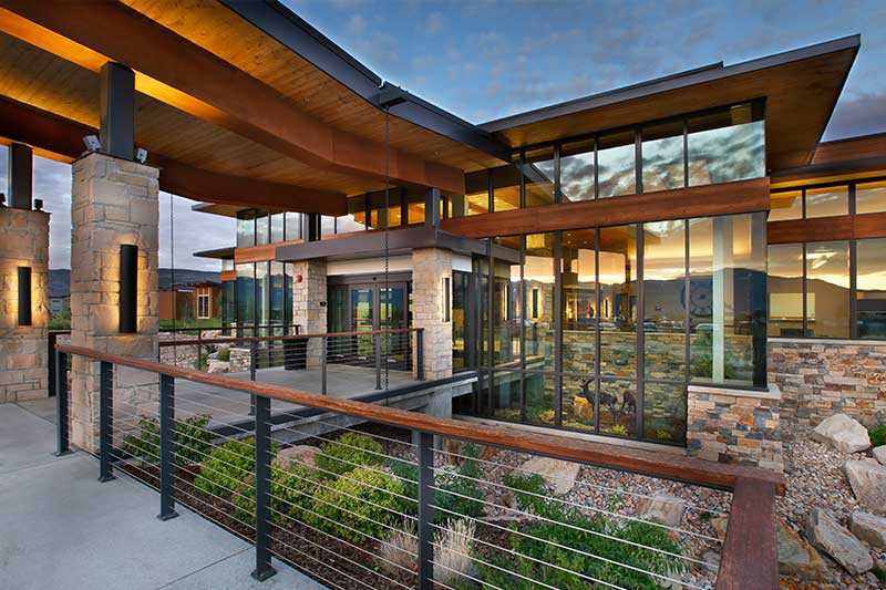 A modern house with large windows showcasing a contemporary design and a scenic sunset view from the outdoor patio.