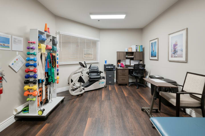 A therapy or rehabilitation office with exercise equipment and a desk.