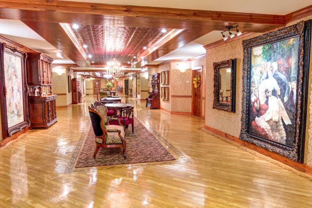 A luxurious hallway with wooden floors, elegant furniture, and decorative artwork and lighting.
