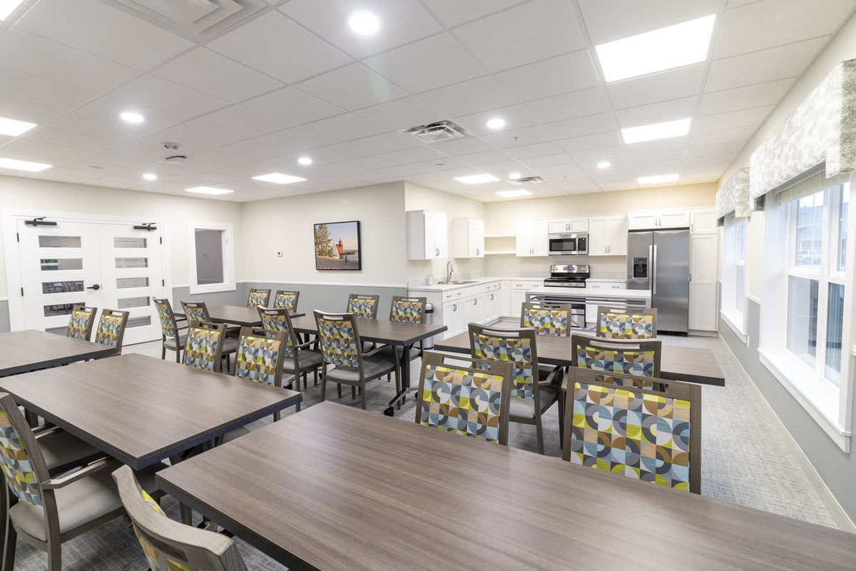 A modern dining area with multiple tables and a kitchen in the background.