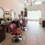 A stylish and modern hair salon with red barber chairs and elegant mirrors.