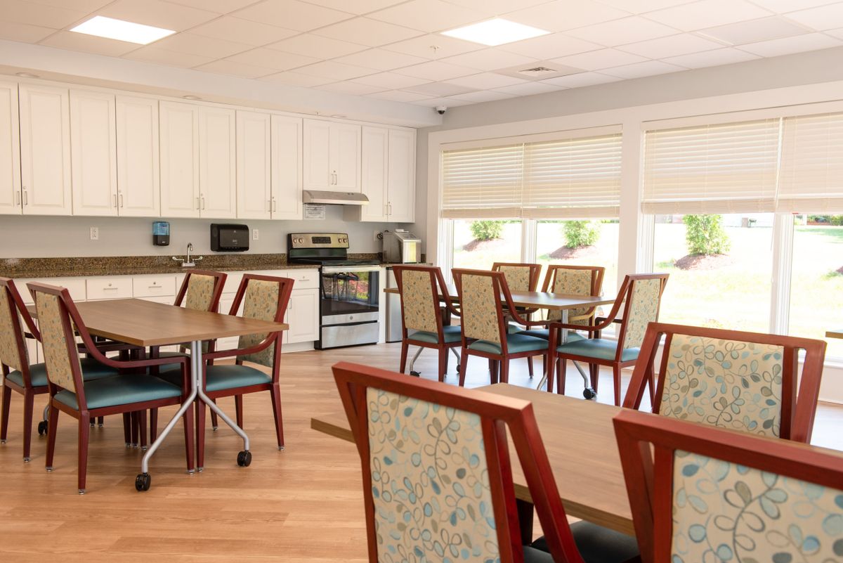 A bright, well-organized kitchen and dining area with tables, chairs, and modern appliances.