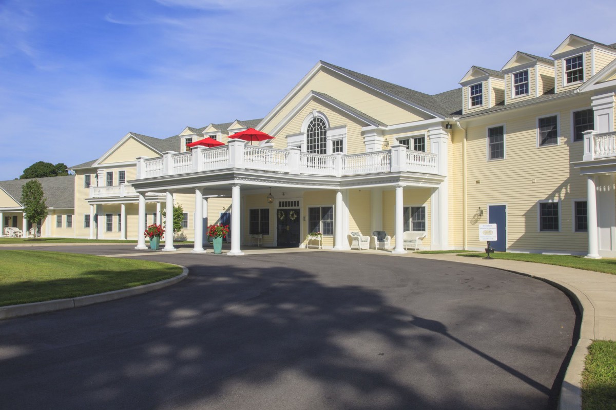 A large residential building with a prominent entrance and balcony during the daytime.