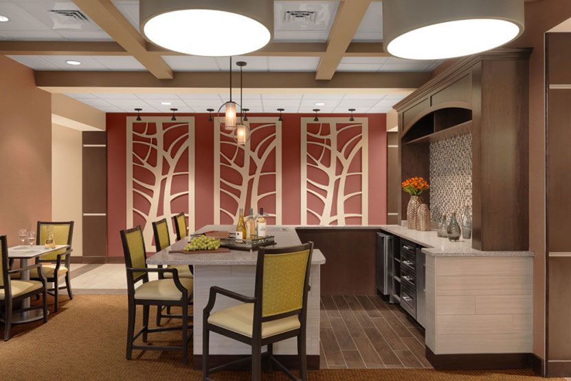 A modern kitchen interior featuring a central island with chairs, decorative art panels, and pendant lighting.